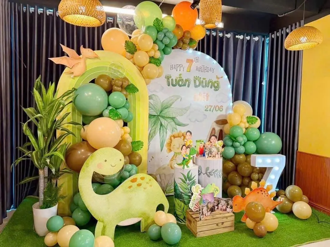 Trang trí sinh nhật chủ đề khủng long với cổng vòm, bong bóng xanh lá, cam, nâu và mô hình khủng long